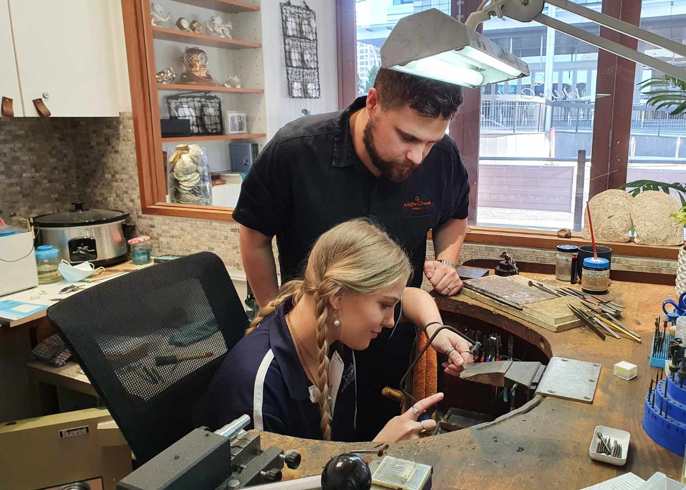 Jeweller teaching apprentice in a workshop