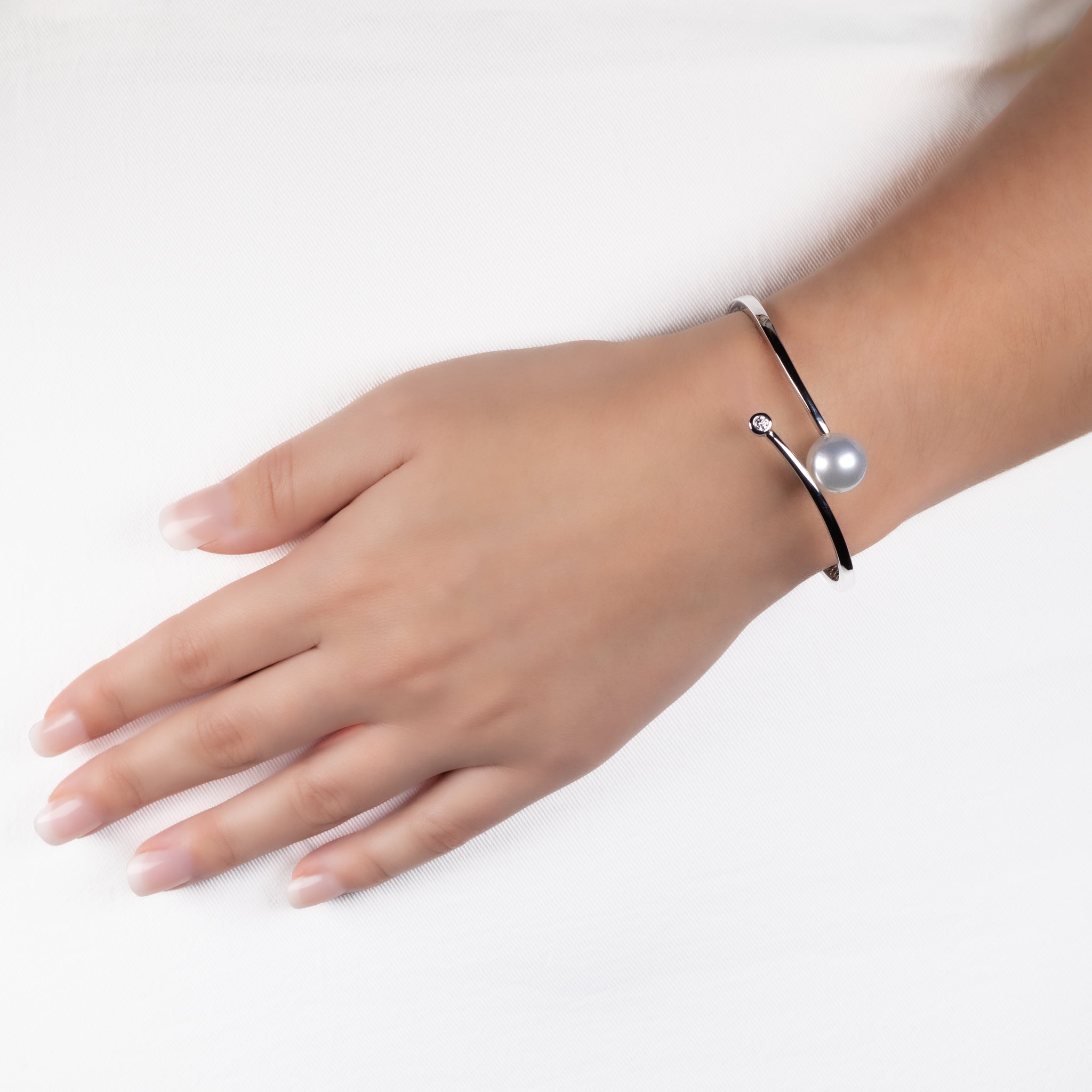 9K White Gold Australian South Sea 12-13 mm Cultured Pearl and Diamond Bangle worn on a model's wrist with a white background