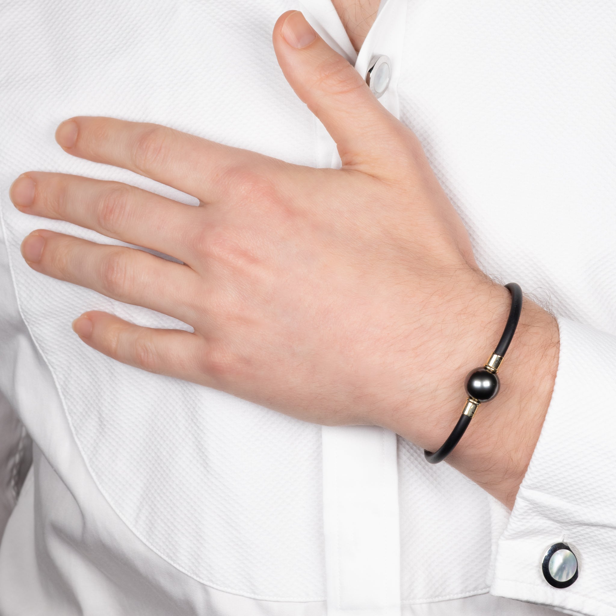 Person wearing a black bracelet with a large bead on a white shirt.