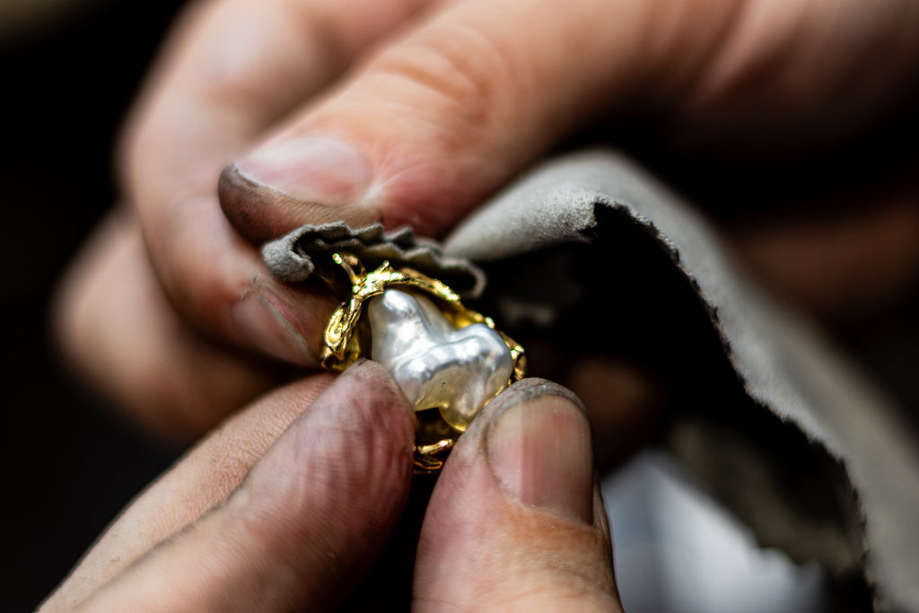 Close-up of hands holding a gold pendant with a Keshi pearl - a piece from our Untamed Collection
