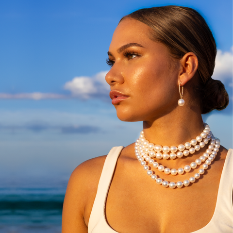 Woman wearing a pearl necklace with a beach background