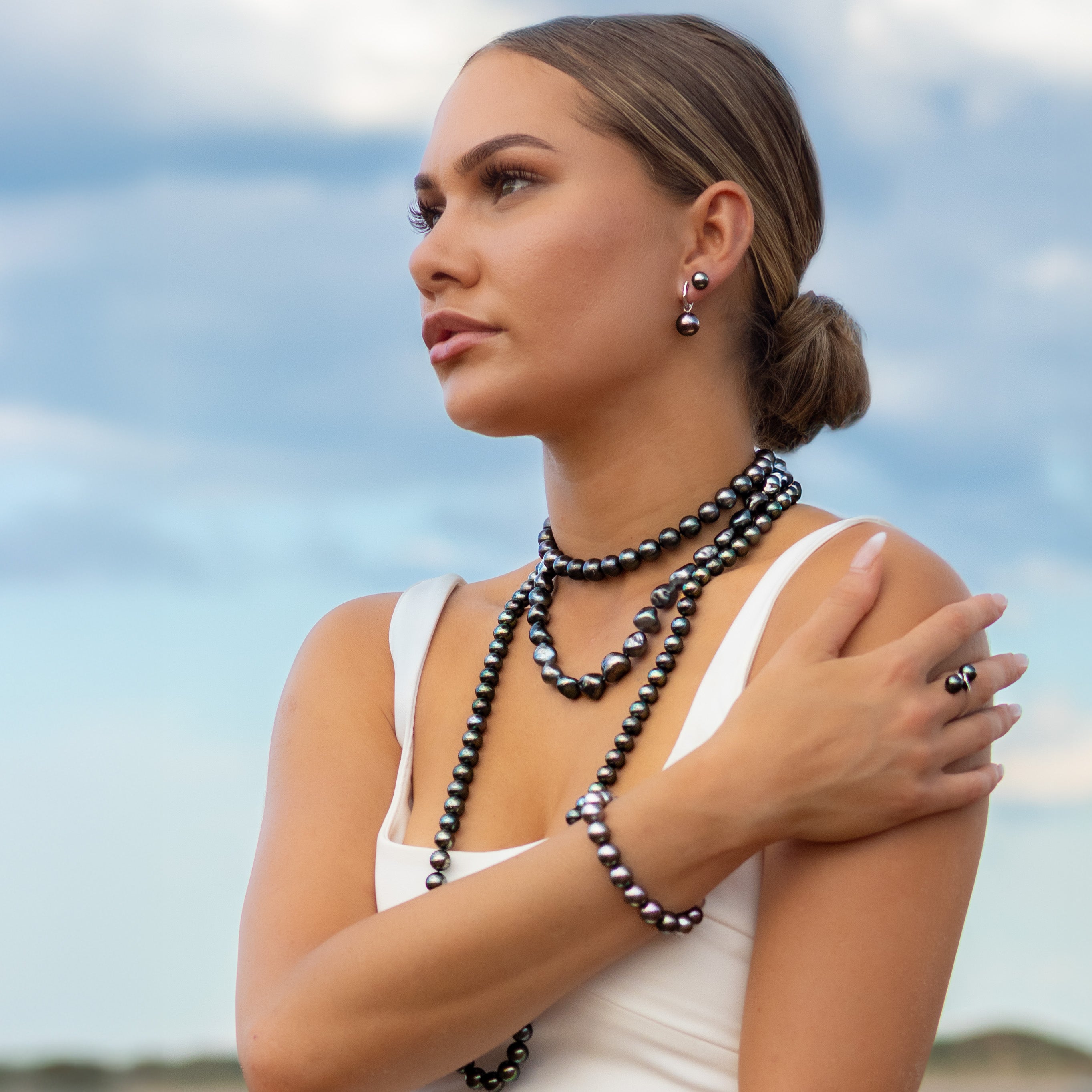 Woman wearing pearl jewelry against a blue sky background