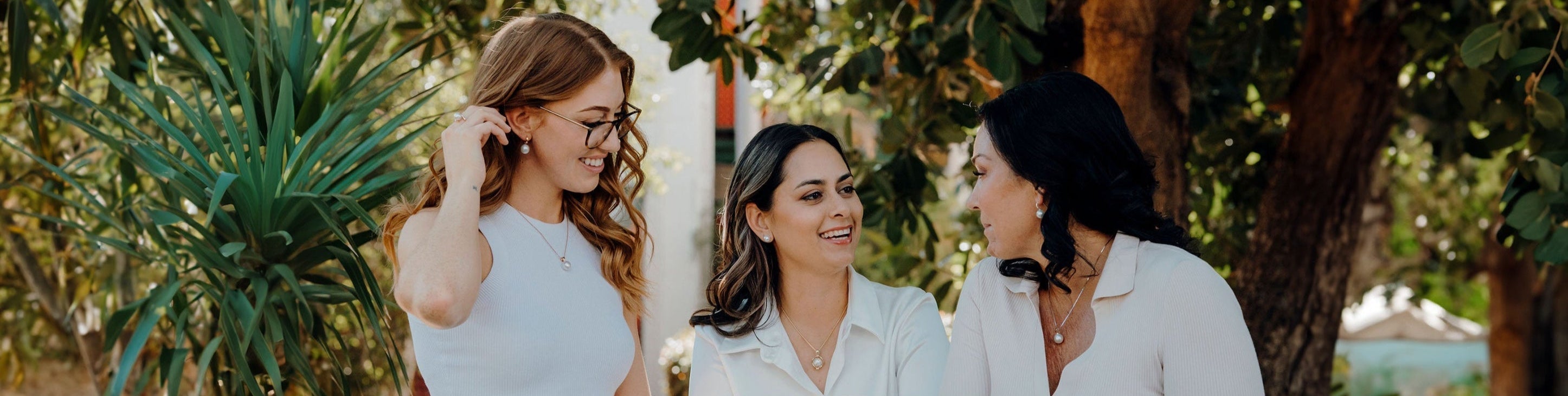 Three women chatting wearing Australian South Sea Jewellery with a tropical background