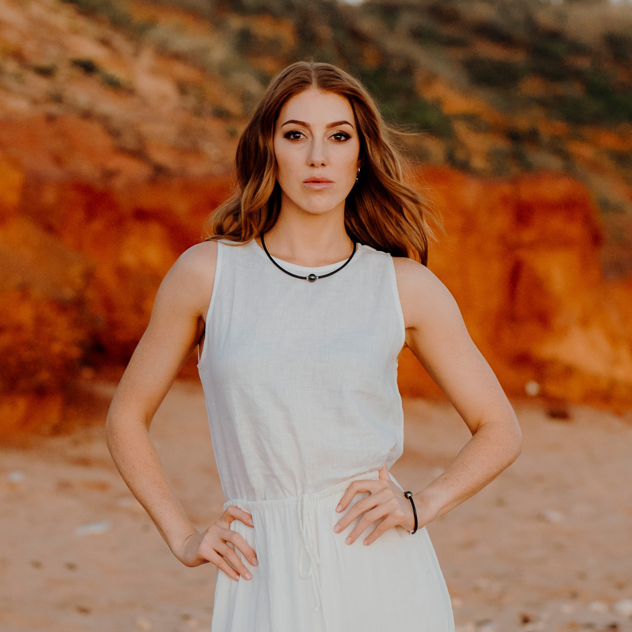 Woman standing in front of Pindan Broome rocks wearing a Tahitian Pearl neoprene necklace and Tahitian Pearl neoprene bracelet