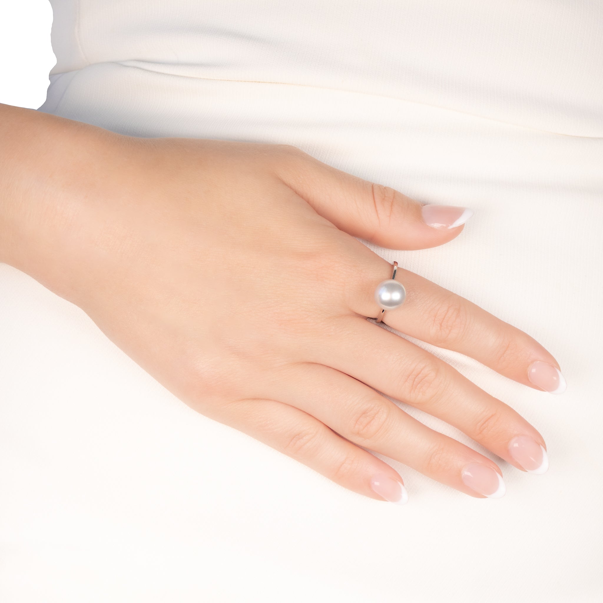 Hand wearing a pearl ring on a white background