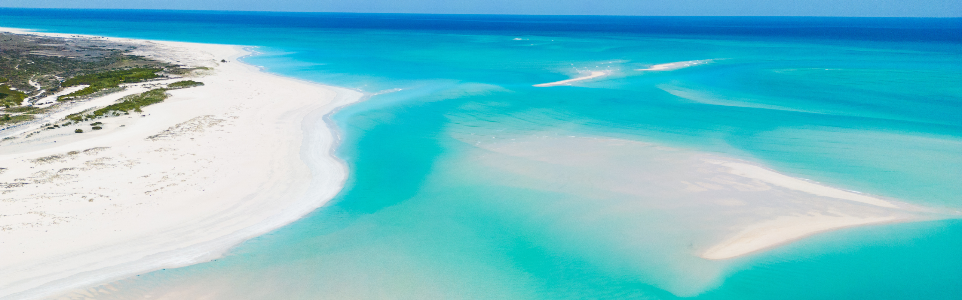 Turquoise waters and white sand beach with clear blue sky