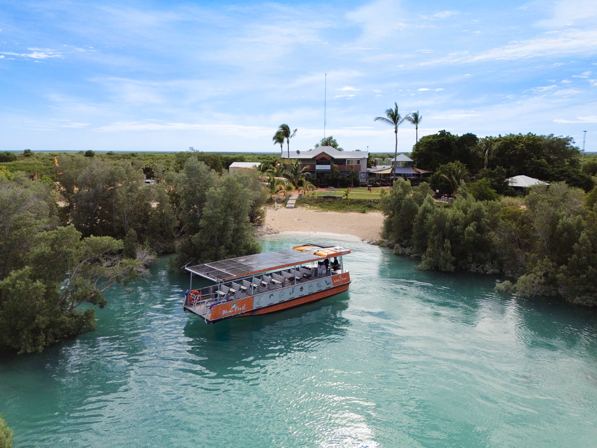 Mimi Pearl Tour boat on a river surrounded by trees and a clear blue sky at the Willie Creek Pearl Farm.
