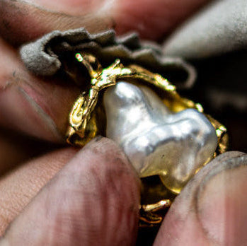 Close-up of hands holding a gold pendant with a Keshi pearl - a piece from our Untamed Collection
